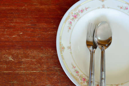 spoon and fork with white plate on wood tableの写真素材