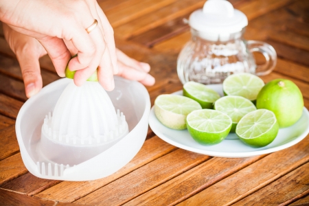 Hand squashing fresh citrus lime on wood tableの写真素材