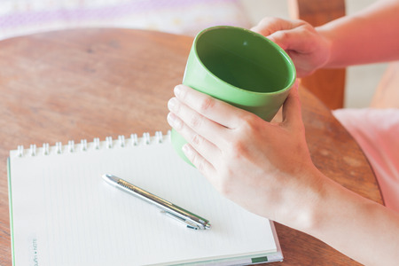 Hand holding green mug in coffee shopの写真素材