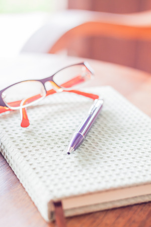 Pen and eyeglasses on notebook, stock photoの写真素材