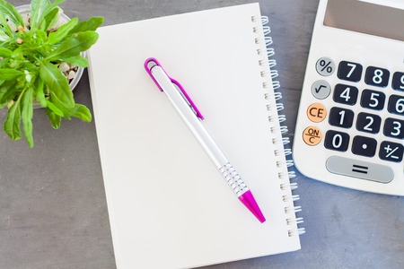 Calculator, notepad,  pen and green plant on grey backgroundの写真素材