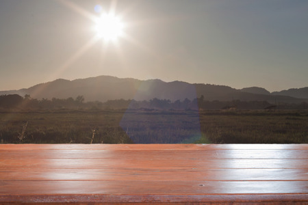 Old empty wooden table top with sunrise and field background, stock photoの写真素材