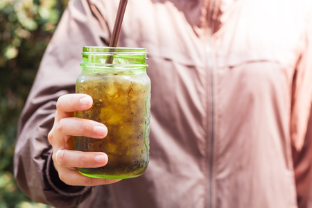 Woman hand holding iced soda in green glass with vintage filter, stock photoの写真素材