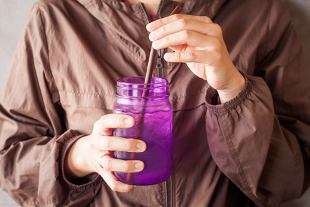 Woman hand holding iced drink in violet glass with vintage filter,  stock photoの写真素材