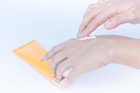 Woman pouring body lotion on hand on white background
