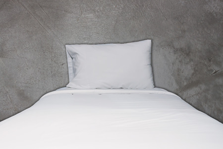 Close up white bedding and pillow on concrete texture backgroundの写真素材