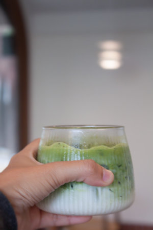 Hand holding iced matcha green tea, stock photo