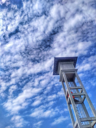 Blue sky with white clouds and a lookout tower in the foreground.の写真素材