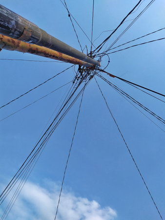 Closeup of an electric pole against a blue sky with clouds.の写真素材