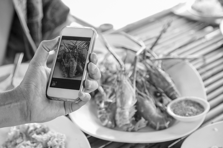 Photography grilled shrimp picture using his smartphone in a restaurantの写真素材