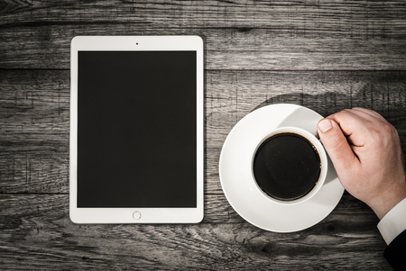 Business workspace concept. Top view. Workplace with tablet and coffee. Business man hand.の写真素材