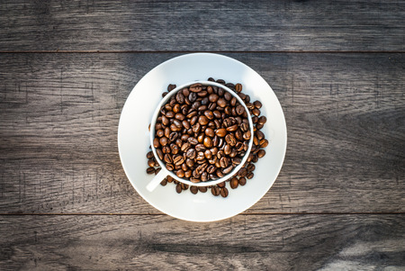 Coffee cup with coffee beans on wooden table background.の写真素材