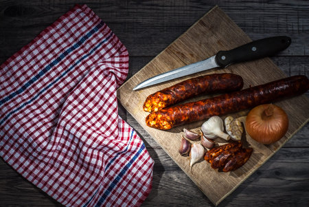 Smoked sausage. Homemade sausage with onion, garlic and kitchen cloth. on wooden table background.の写真素材