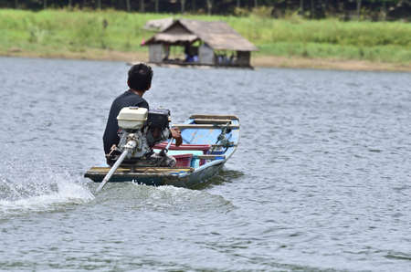 man driving fishing boat in lakeの写真素材
