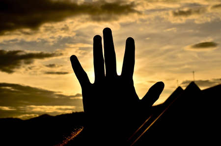 sunset covered with hand in silhoueteの写真素材