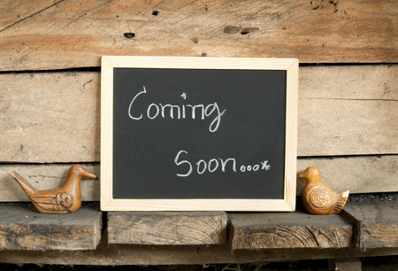 blackboard writing word "coming soon" on wooden wall backgroundの写真素材