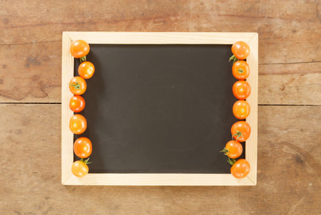 empty blackboard and fresh tomato on wooden wall backgroundの写真素材