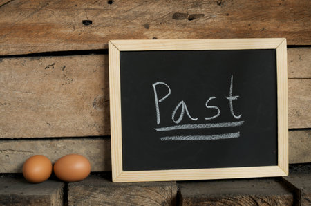 blackboard writing word "Past" and eggs on wooden wall backgroundの写真素材