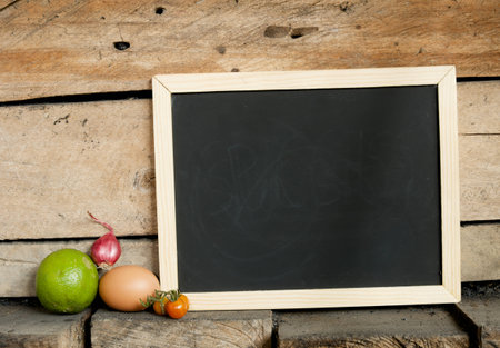 empty blackboard and ingredients on wooden wall backgroundの写真素材