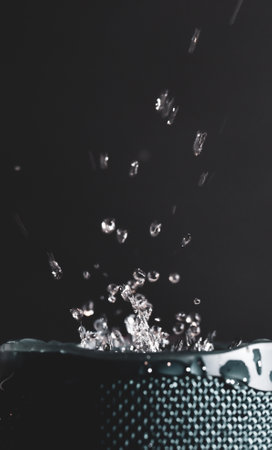 Liquid splash on a waterproof speaker with dark backgroundの写真素材