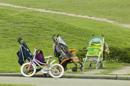 Kyiv Ukraine - May 2, 2018: Different baby carriages and bike in park on green grass backgroungのeditorial素材
