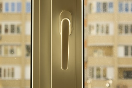 White plastic window handle, window wirh dirthy glasses, view from window on another building in backgroundの写真素材