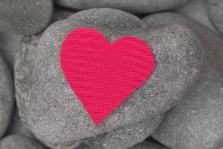 Pink textile texture heart close up on a grey sea stones backgroundの写真素材