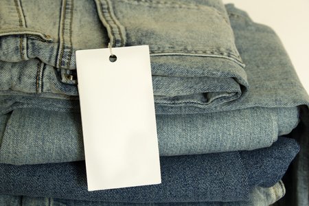A stack of new jeans with white paper tag mockup and copy spaceの写真素材