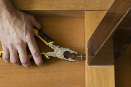 The hands of a carpenter repairing old furniture with pliers tool,の写真素材