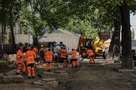 Construction site with workers in orange uniform and construction machinery