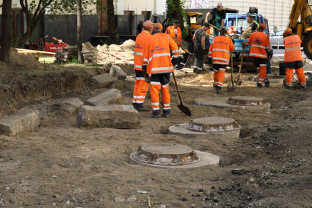 Construction site with workers in orange uniform and construction machinery