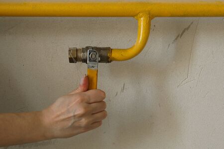 Woman turning on or turning off gas supply on yellow gas pipe close upの写真素材
