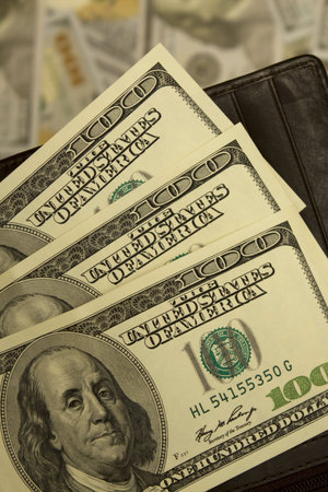Dollar banknotes in leather wallet on money background close up