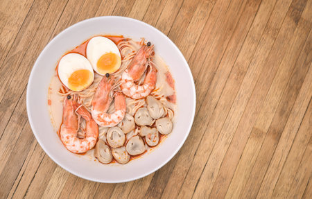 Creamy Shrimp Ramen with egg and mushroom on wood background.