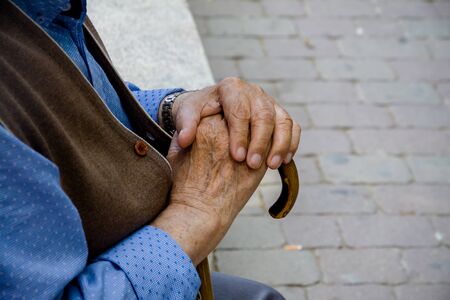 Old man sitting and holding a stickの写真素材
