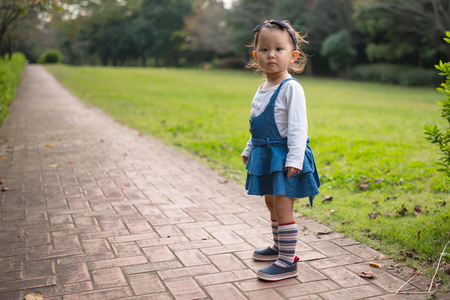 Portrait of little girl outside, standing at the brick roadの写真素材