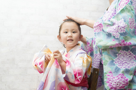 Mother helping her daughter to get dressed in yukataの写真素材