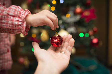 Close up of hands decorating the Christmas tree, Merry Christmas and Happy Holidaysの写真素材