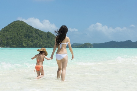 Mother and daughter playing on a beautiful beachの写真素材