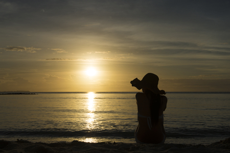 A woman relaxing at the sunset beachの写真素材