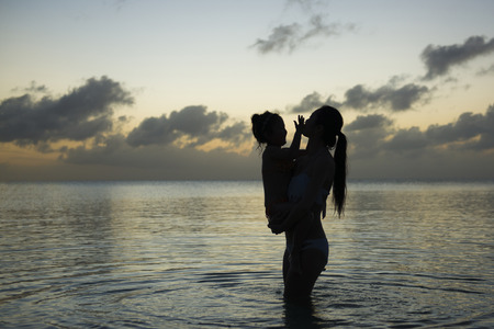 Mother and daughter playing at the sunset beachの写真素材