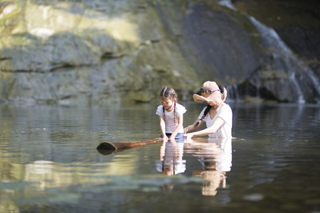 Mother and daughter playing in mountain streamの写真素材