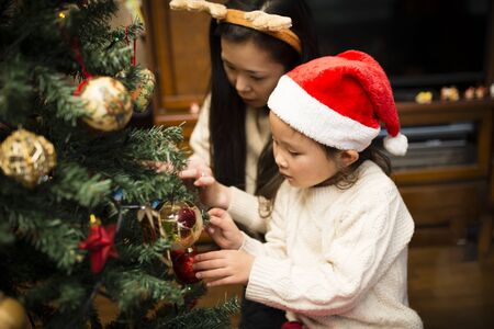 Mother and daughter decorating Christmas treeの写真素材