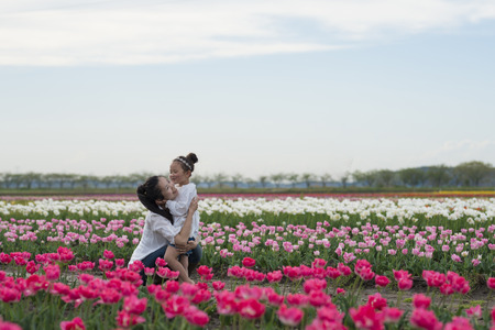 Mother and daughter playing in the tulip fieldの写真素材