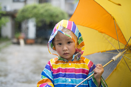 Pretty little girl holding an orange umbrellaの写真素材