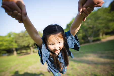 Little girl is spinning and smiling, Father is holding her handsの写真素材