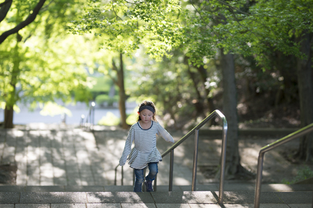 Little girl climbing stairs in beautiful sunny dayの写真素材