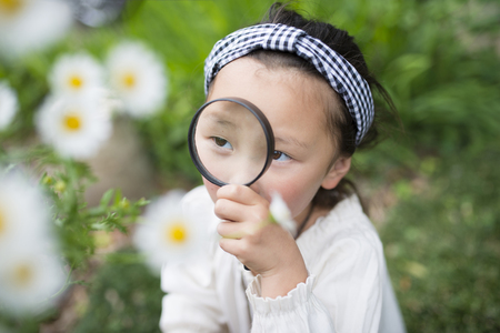 Little girl looking in a magnifying glassの写真素材