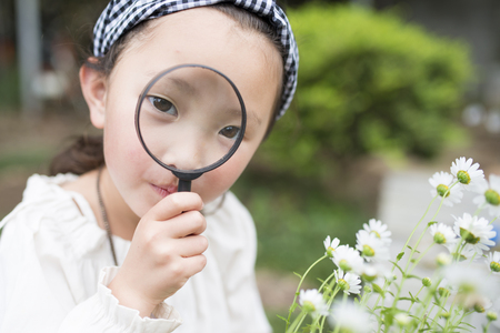 Little girl looking in a magnifying glassの写真素材