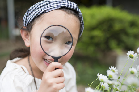 Little girl looking in a magnifying glassの写真素材